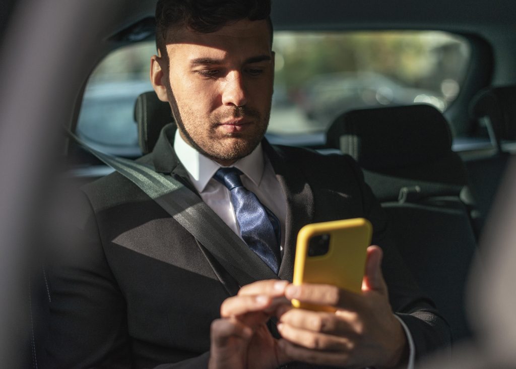 Corporate professional managing business on a mobile phone during executive chauffeur transfer with Ace Cars Reading.